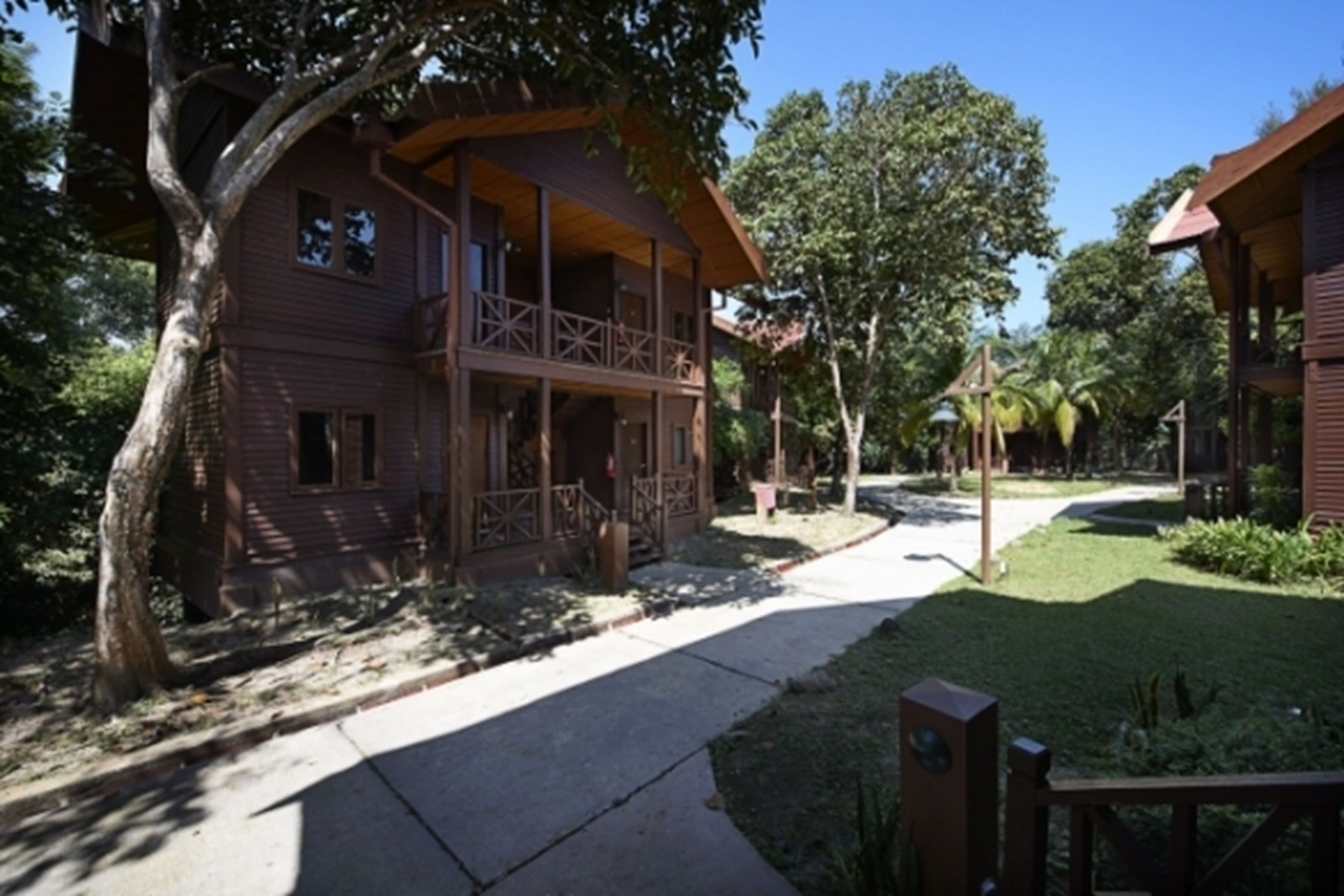 A wooden cabin with a balcony, surrounded by trees and a clear sky.