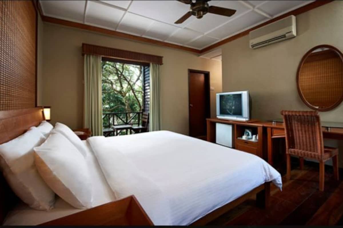 A hotel room with a bed, a desk, a television, and a chair.