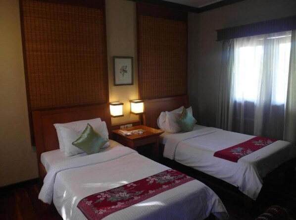 A hotel room with two beds, wooden headboards, a nightstand with a lamp, and a window with curtains. - Redang Island Resort (Redang Island)