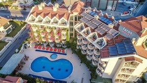Un hotel con piscina en la azotea, varios balcones y un patio central con tumbonas.