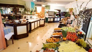 Montaje de bufé con diversos alimentos y un chef preparando comida.