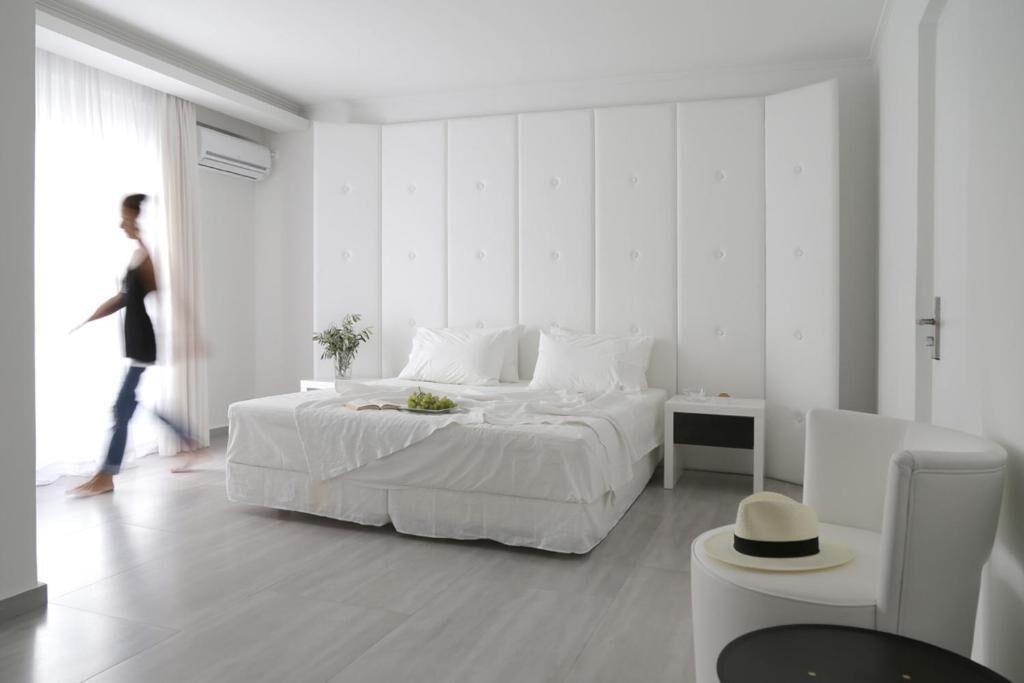 Un dormitorio moderno con una cama grande, mesitas de noche, una silla y una ventana con cortinas.
