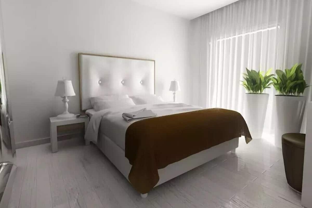 A modern bedroom with a bed, nightstands, and a window with curtains.