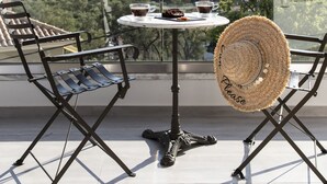 Un balcon avec une table, des chaises et un chapeau de paille.