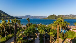 A coastal resort with a view of the sea, palm trees, and mountains in the background.