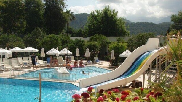 Une piscine avec un toboggan, des chaises longues et des parasols.