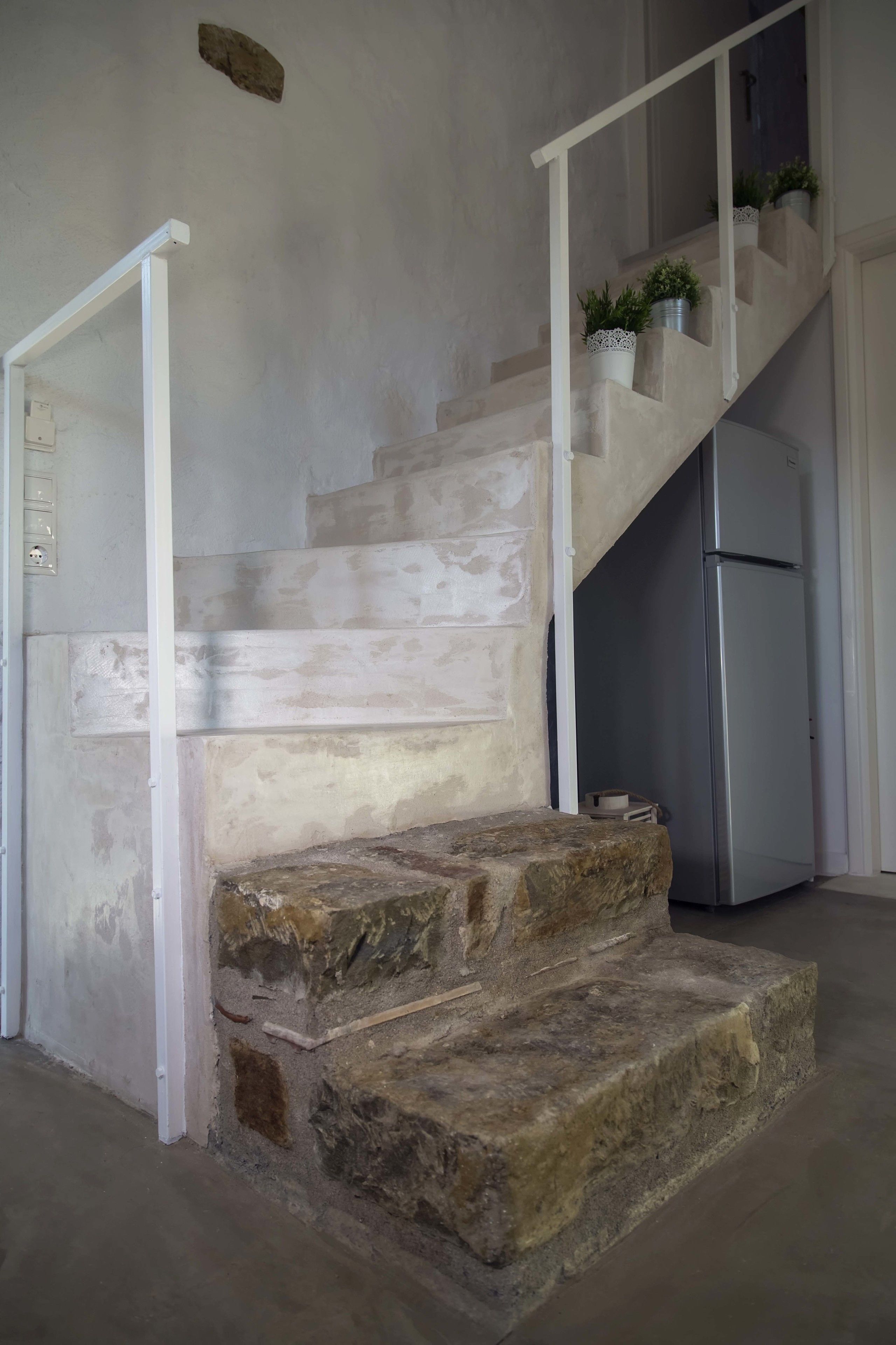 Un escalier avec des marches en pierre et une rampe blanche, menant à un deuxième étage.