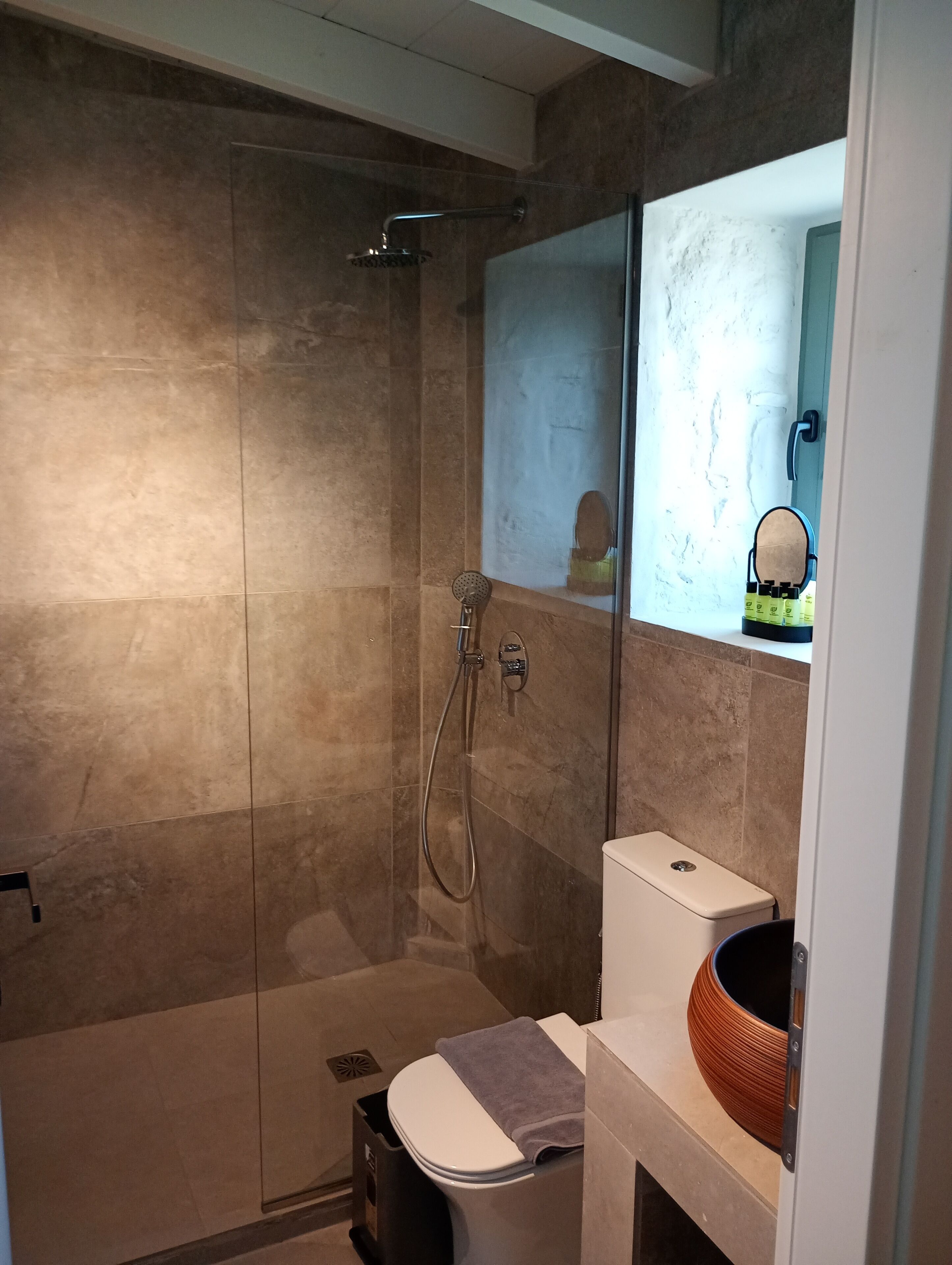 Une salle de bain moderne dotée d’une douche à parois de verre, de toilettes et d’un lavabo agrémenté d’un récipient décoratif.