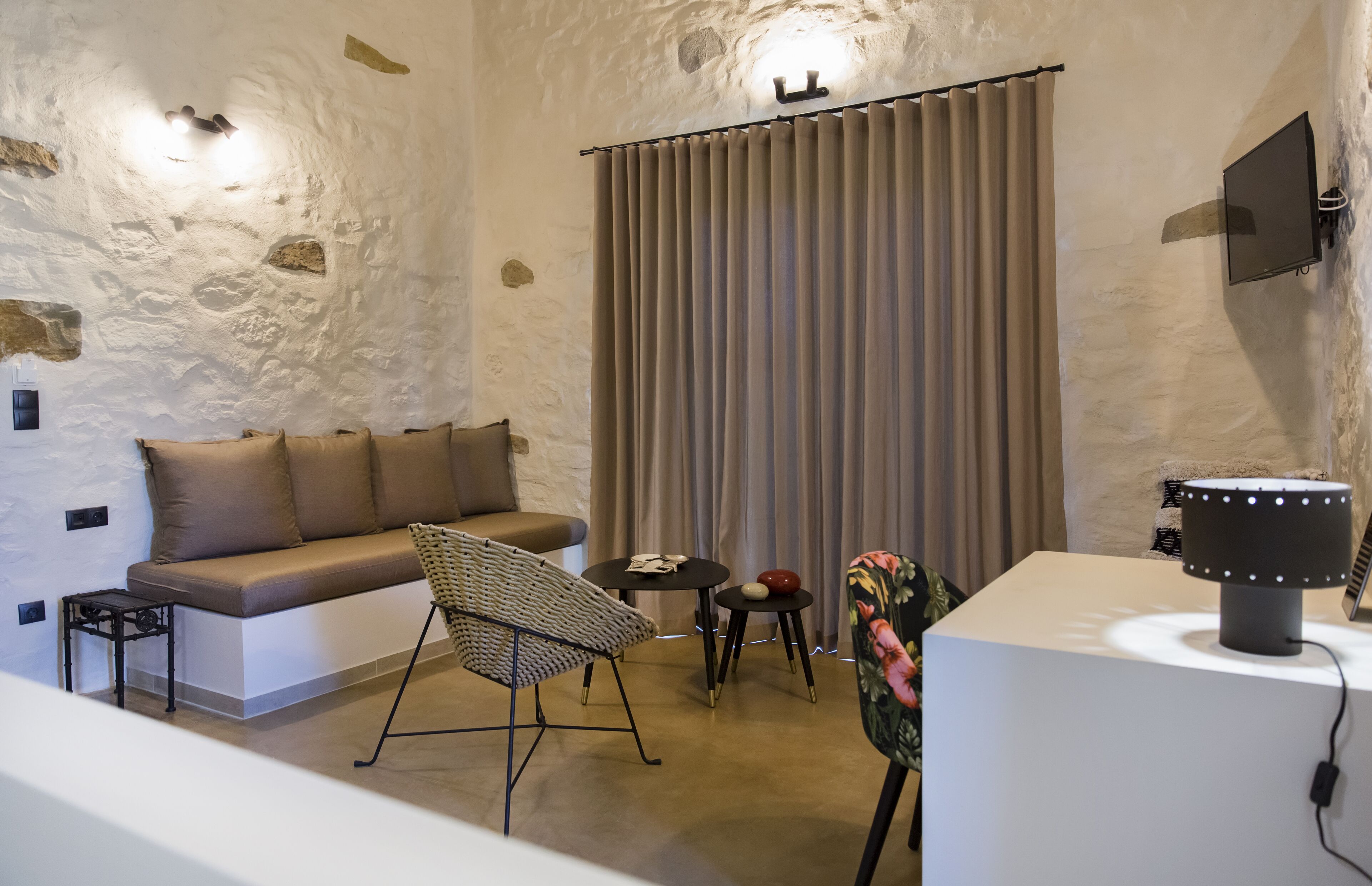 A cozy room with a sofa, a chair, a small table, a television, and a lamp.
