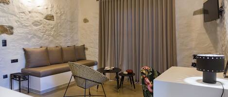 Una habitación acogedora con sofá, sillón, una mesita, televisor y lámpara.
