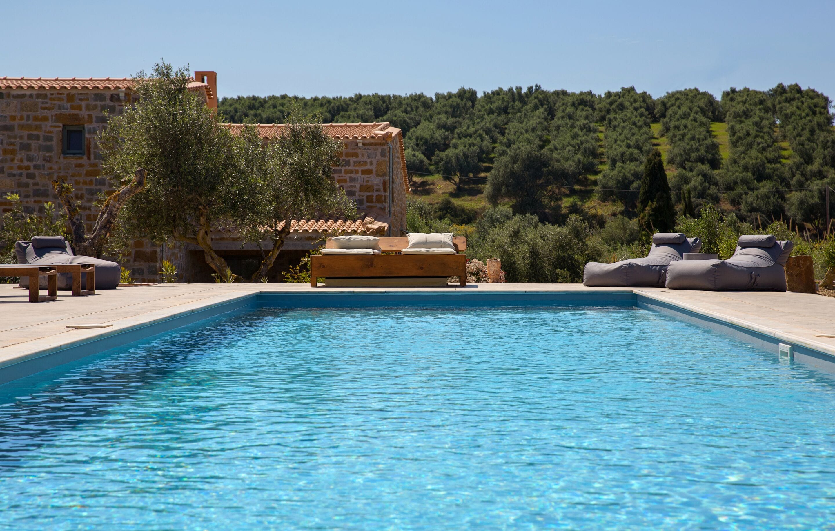 A swimming pool with lounge chairs and a stone building in the background.