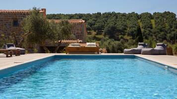 A swimming pool with lounge chairs and a stone building in the background.