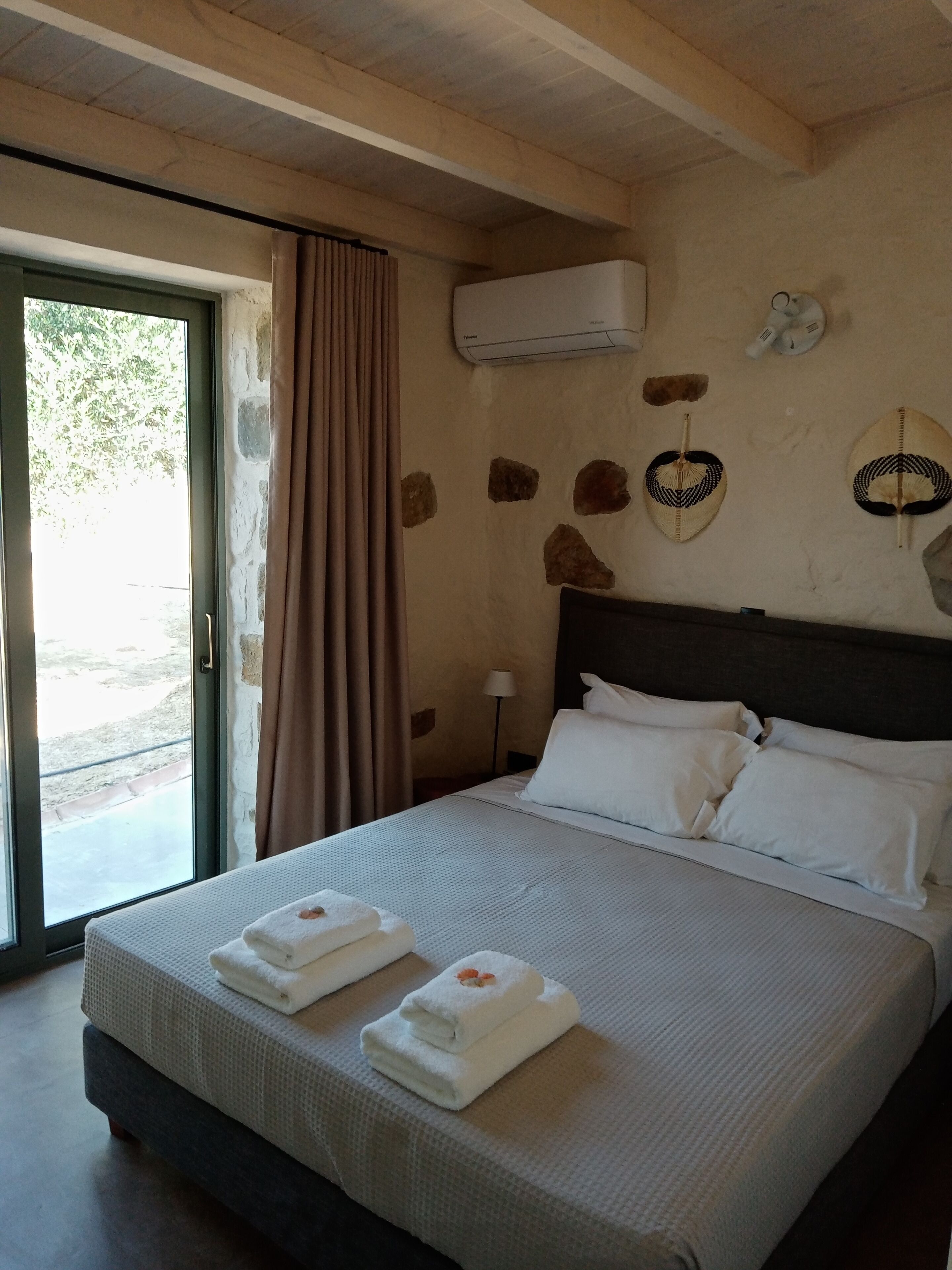 Una habitación de hotel con cama, ventana con cortinas, equipo de aire acondicionado y decoración en la pared.