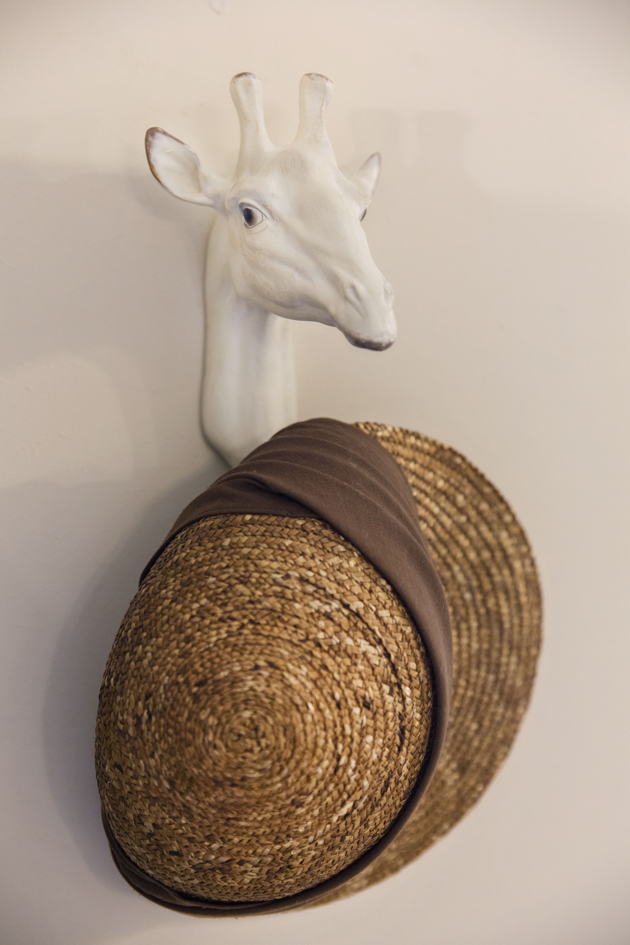 Een girafbeeld op een muur, naast een geweven mand.