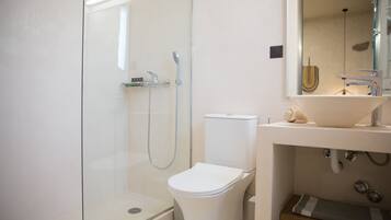 A modern bathroom with a glass-enclosed shower, a white toilet, and a sink with a mirror above it.