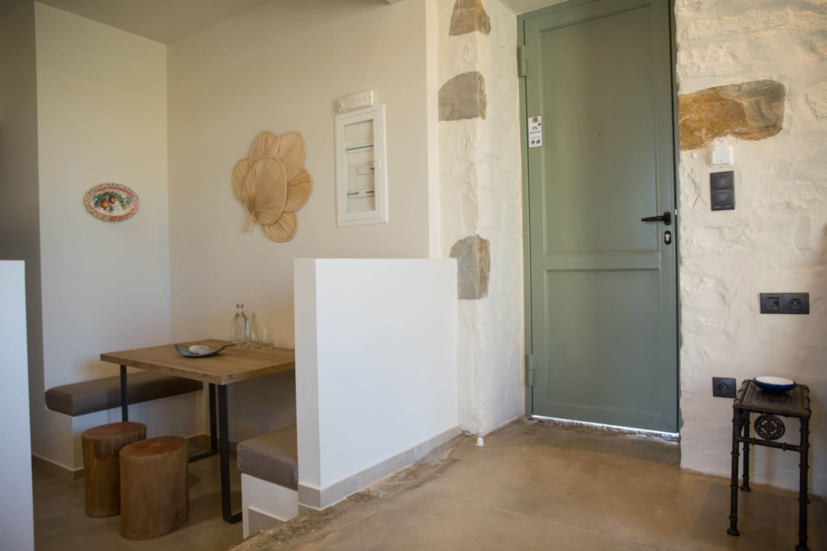 A small, cozy room with a wooden table, a bench, and a door.