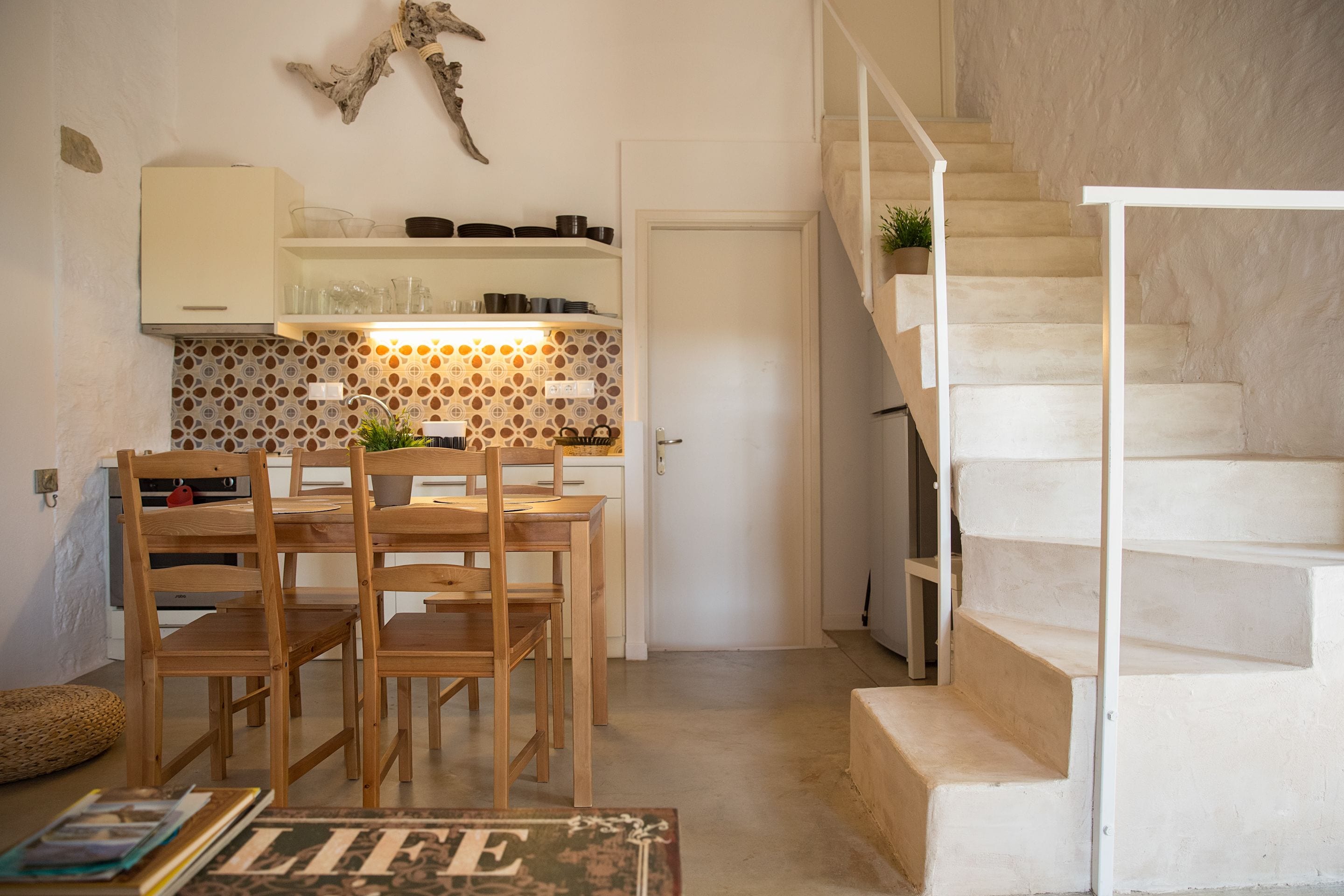 Une cuisine avec des chaises en bois, une table à manger et un escalier menant à l’étage supérieur.