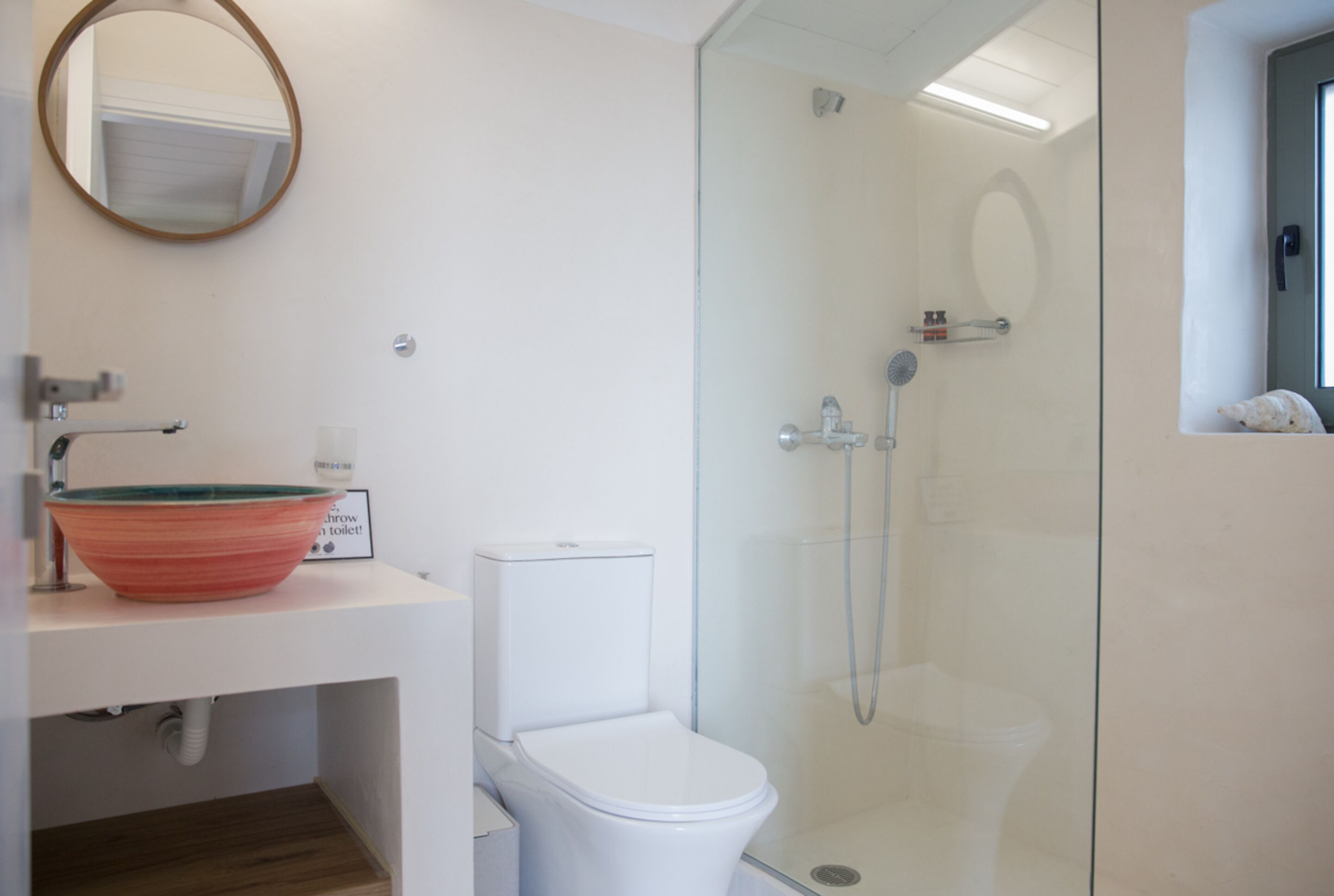 A bathroom with a glass-enclosed shower, a white toilet, and a sink with a bowl.