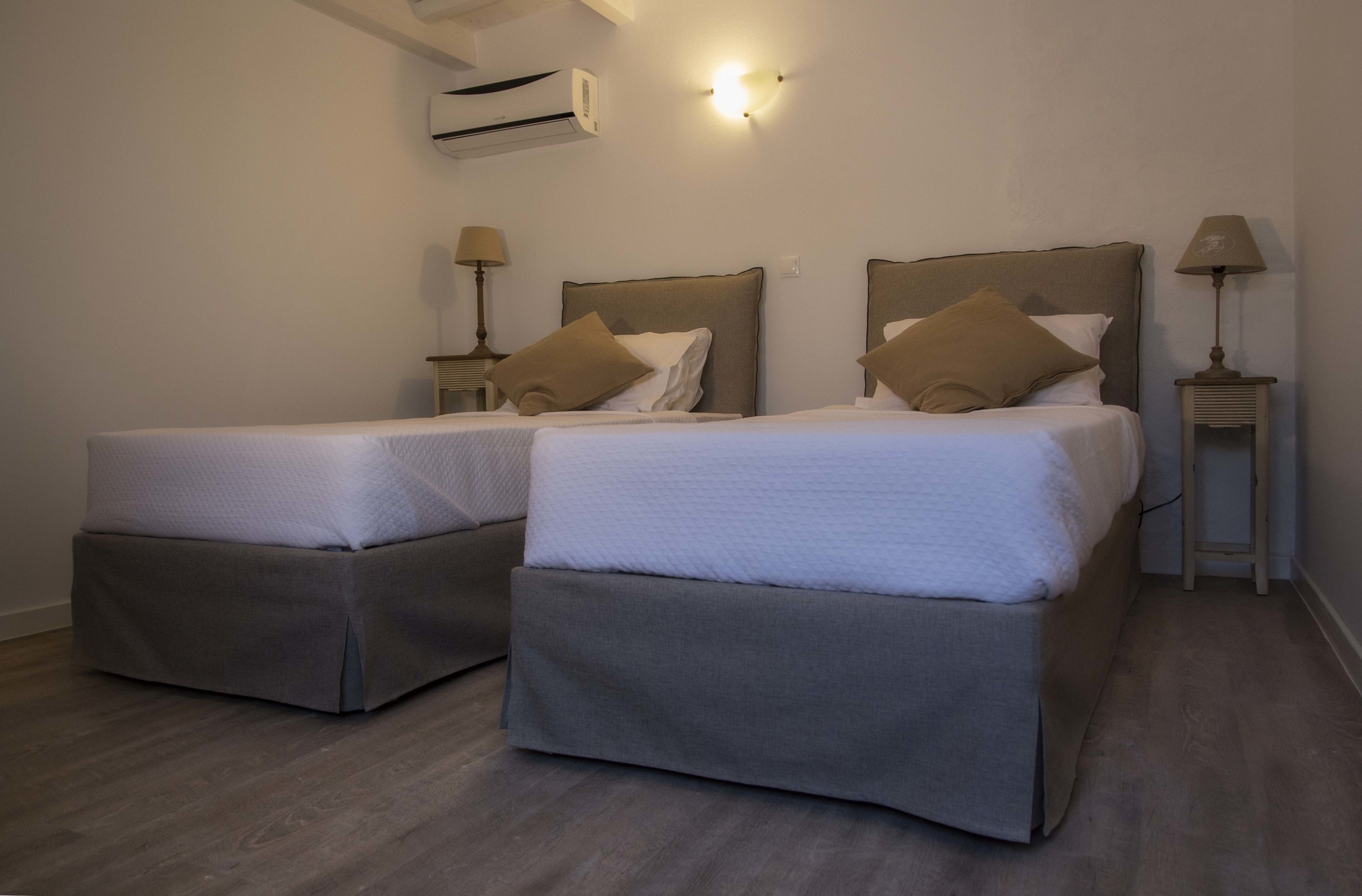 A hotel room with two beds, each with a headboard, bedside tables, and lamps.