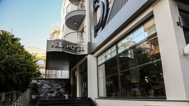 Exterior del ASL Hotel, con un diseño moderno, que presenta un cartel llamativo, una escalera que conduce a la entrada y grandes ventanales que reflejan el entorno.