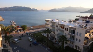Un edificio costero con varios pisos, balcones y vistas al mar y a las montañas.
