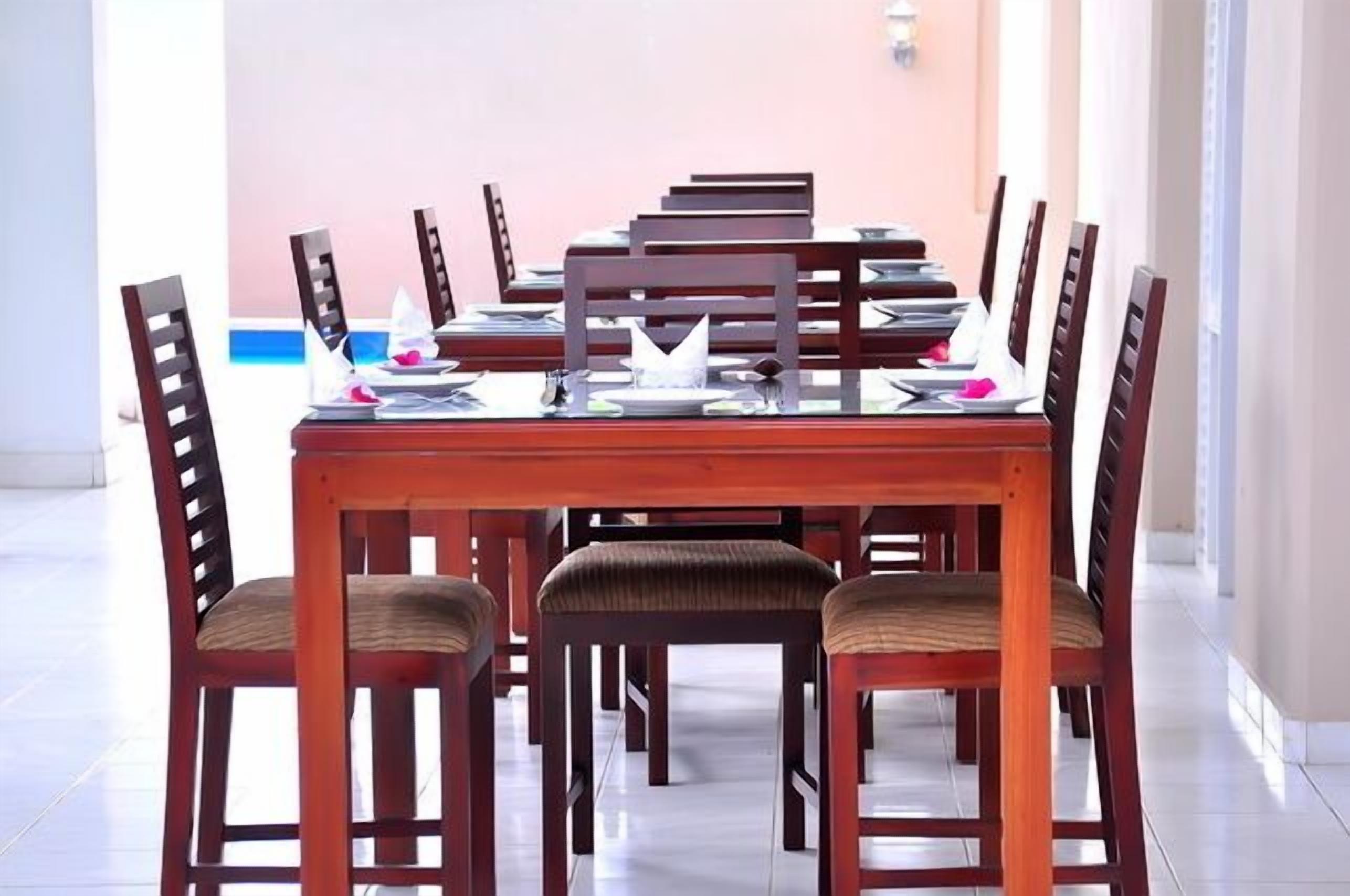 Un espace repas avec une longue table en bois et des chaises, disposées pour un repas.