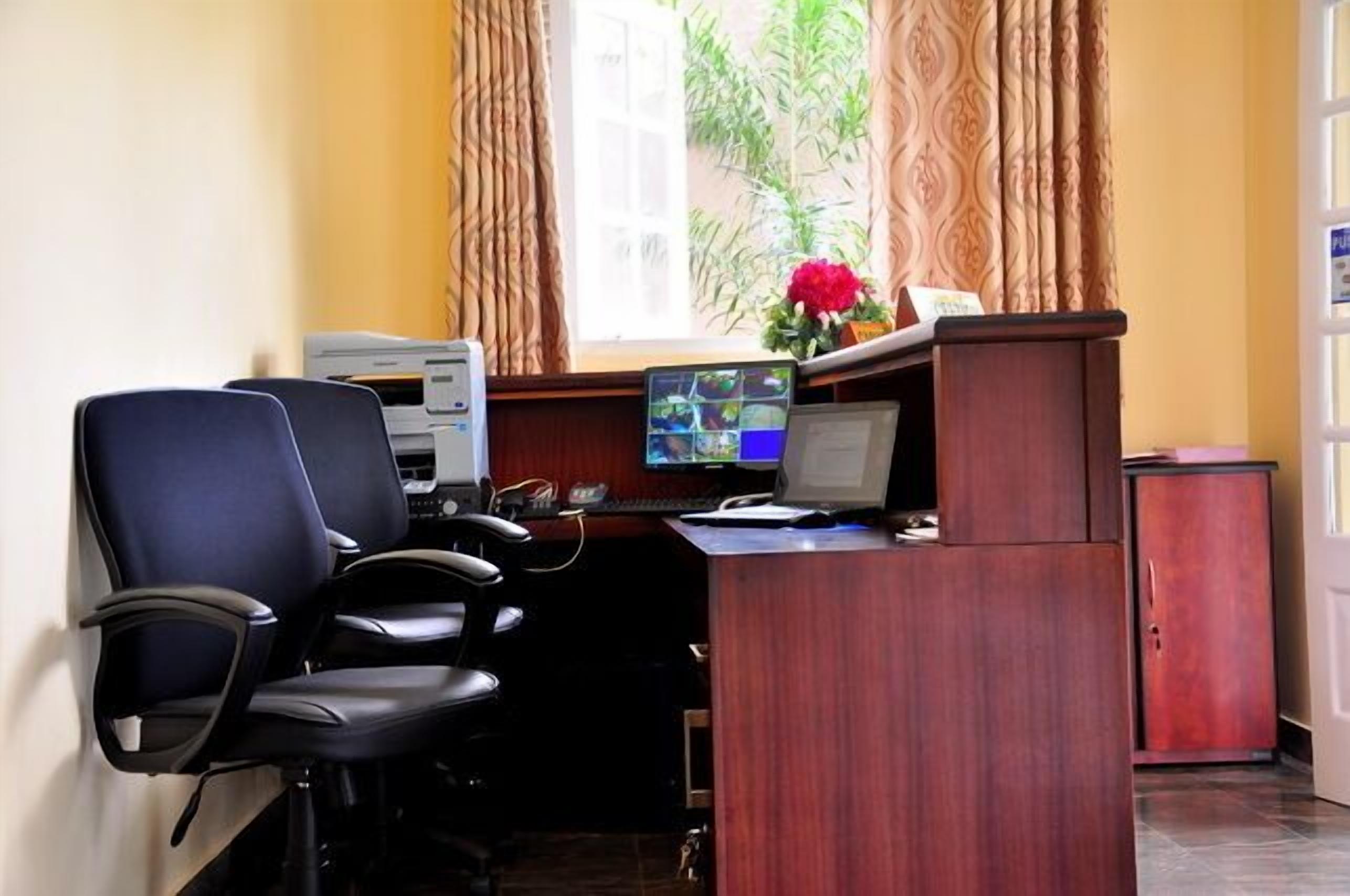 Una habitación con un escritorio, dos sillas, una computadora, una impresora y un mueble bajo.