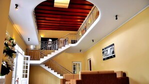 Ein großzügiger Innenraum mit einer geschwungenen Treppe, einer Sitzecke und einem gerahmten Bild an der Wand.