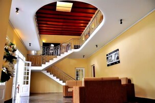 Un interior amplio con una escalera curva, una zona de estar y un cuadro enmarcado en la pared.