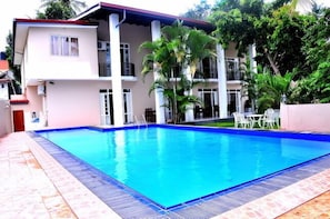 A swimming pool with a blue border, surrounded by a tiled deck. - Grand 7 Hotel - Thalawathugoda (Thalawatugoda)