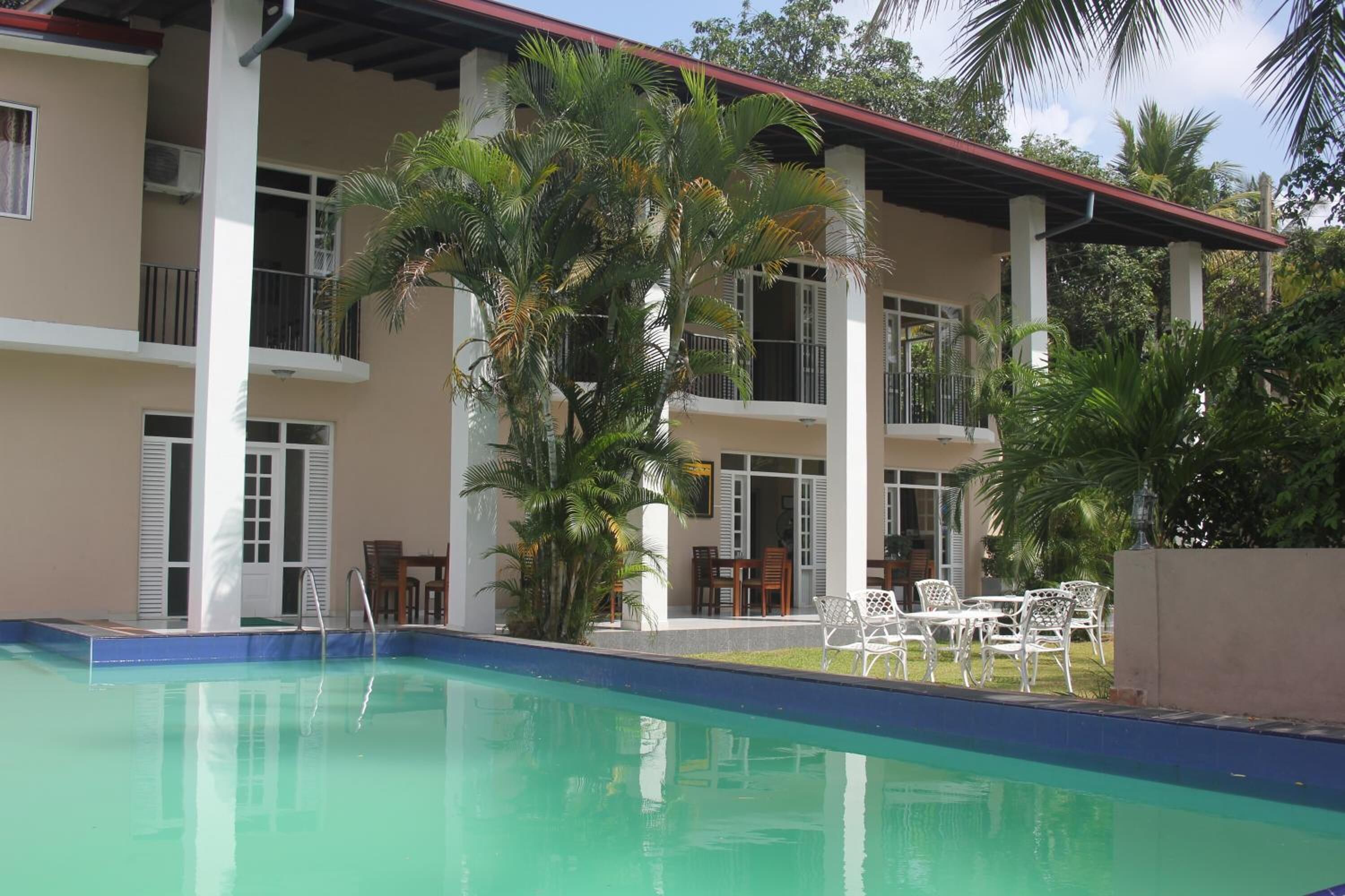 Ein Hotel mit Schwimmbad, Außenbereich und Palmen.