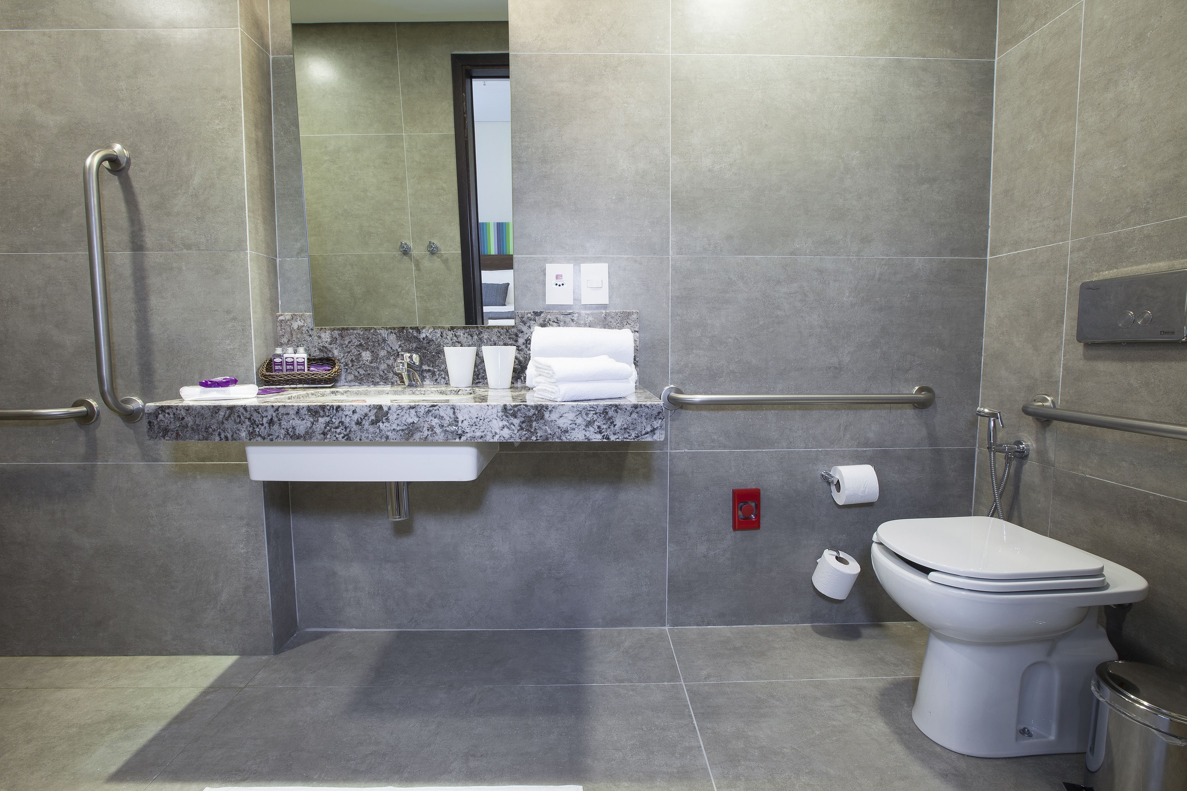 Um banheiro moderno com bancada de mármore, vaso sanitário branco e área de chuveiro.