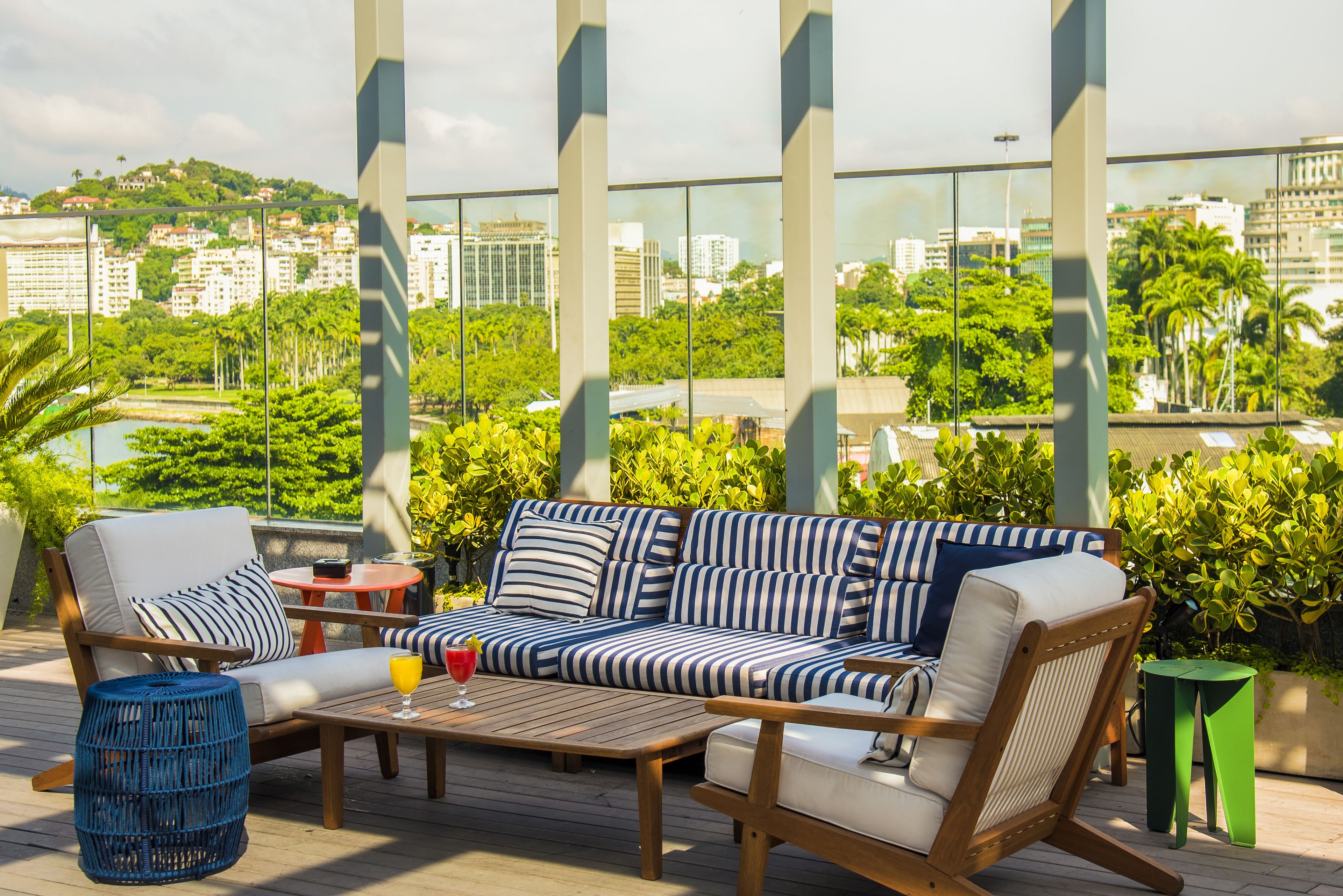 Une terrasse sur le toit, avec un canapé à rayures, des chaises en bois et une table sur laquelle se trouve une boisson.
