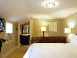 Quarto de hotel com uma cama grande, uma mesa de escritório com computador, televisão e banheiro com espelho e pia.