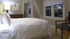 A bedroom with a bed, a chair, a lamp, and a window. - Mooncussers Tavern and Inn (Harwich Port)