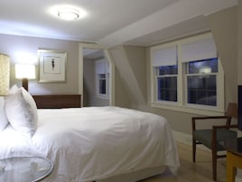 Quarto com cama, cadeira, abajur e janela.
