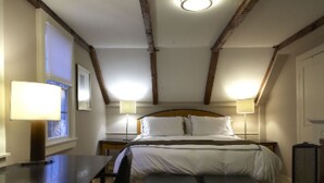 A bedroom with a bed, two bedside tables with lamps, a desk, and a chair. - Mooncussers Tavern and Inn (Harwich Port)