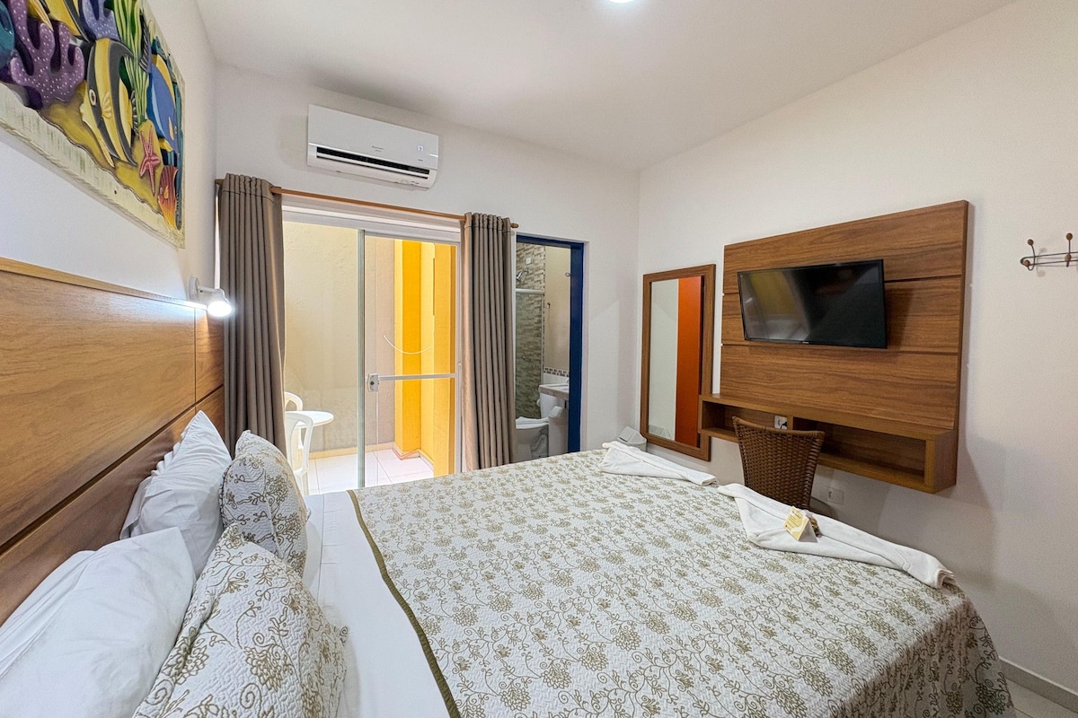 A hotel room with a bed, a television, a shower, and a bathroom.