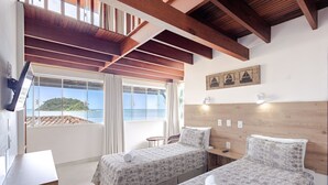 A room with two beds, a small table, a chair, and a large window overlooking the sea. - Pousada Kaliman Ubatuba (Ubatuba)