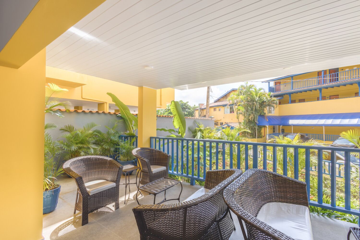 A covered outdoor seating area with wicker furniture and potted plants.
