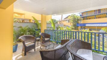 A covered outdoor seating area with wicker furniture and potted plants.