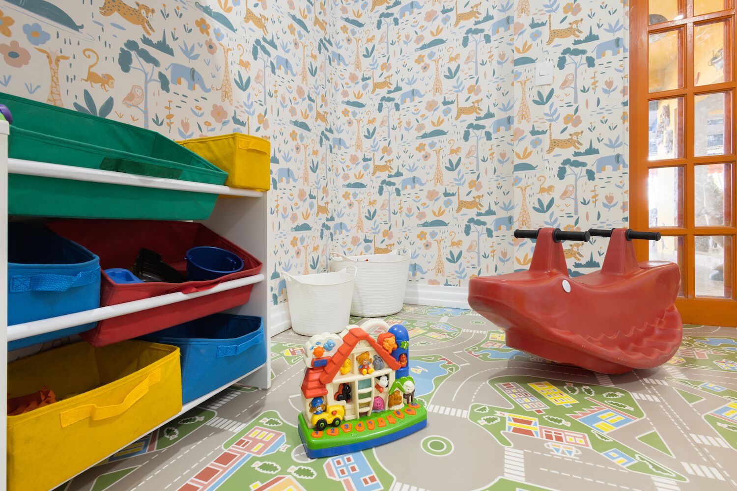 A child's play area with storage bins, a toy train set, and a red rocking horse.