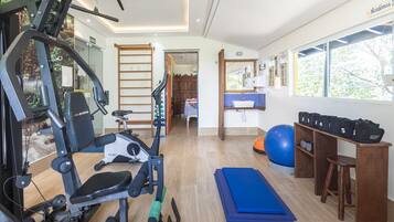 A home gym with exercise equipment, a blue mat, and a wooden bench.