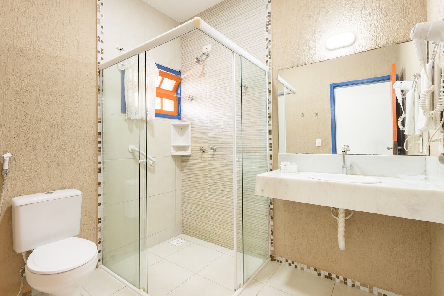 A bathroom with a glass-enclosed shower, a toilet, and a sink with a mirror.