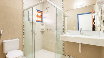 A bathroom with a glass-enclosed shower, a toilet, and a sink with a mirror.