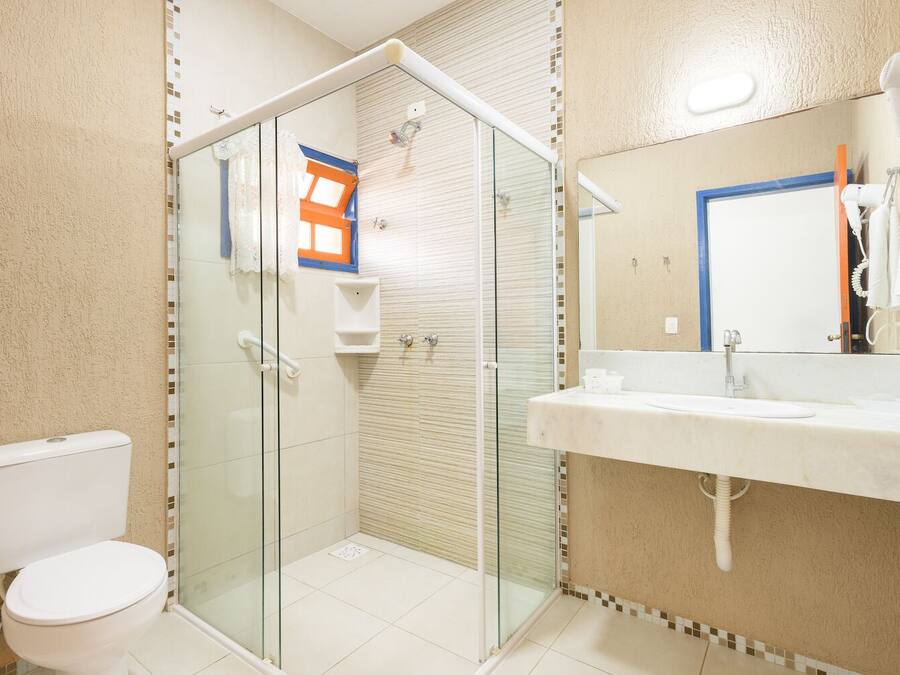 A bathroom with a glass-enclosed shower, a toilet, and a sink with a mirror.