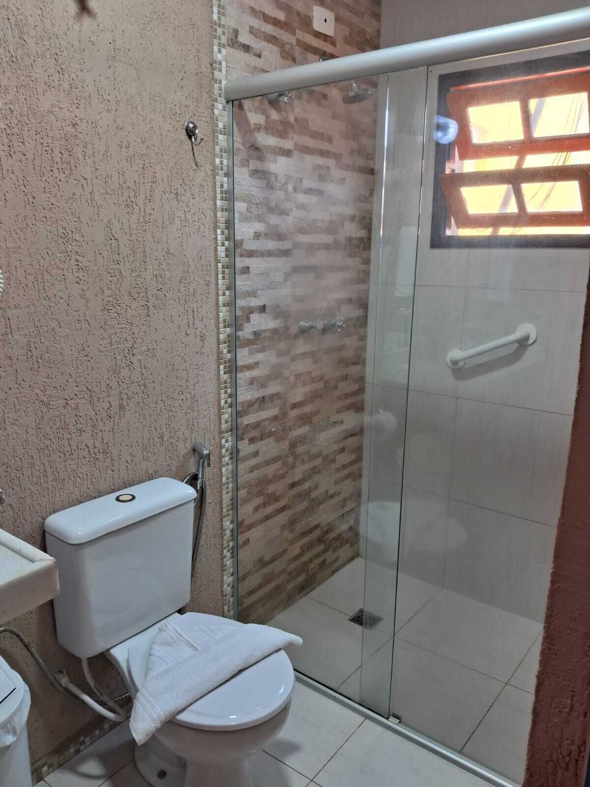 A bathroom with a toilet, a shower enclosure, and a tiled floor.