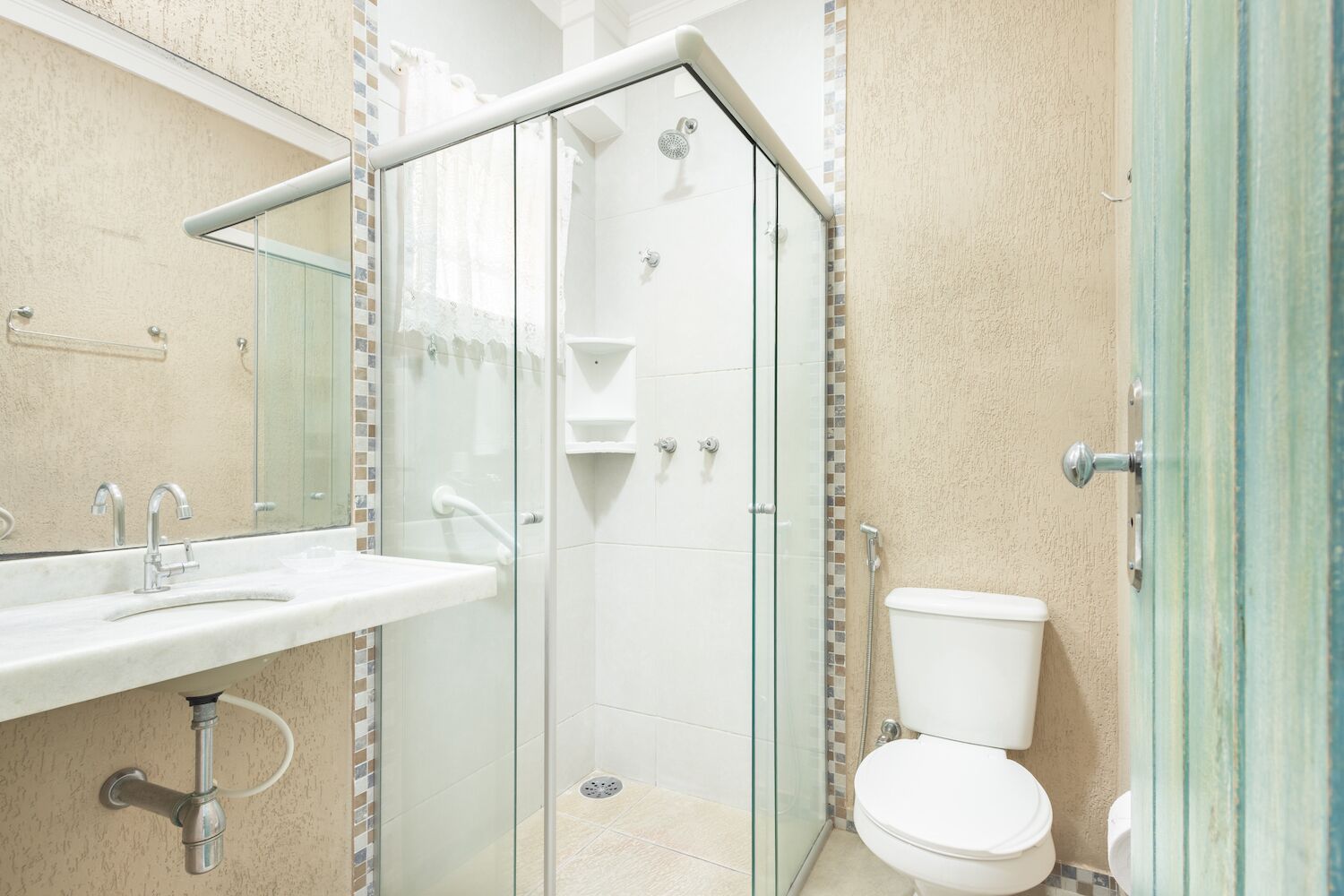 A modern bathroom with a glass-enclosed shower, a white sink, and a toilet.