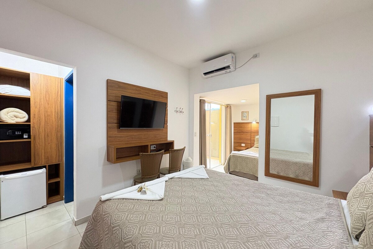 A hotel room with a bed, a television mounted on the wall, a wardrobe, and a mirror.