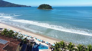 A beach resort with a swimming pool, umbrellas, and a view of the sea and an island. - Pousada Kaliman Ubatuba (Ubatuba)